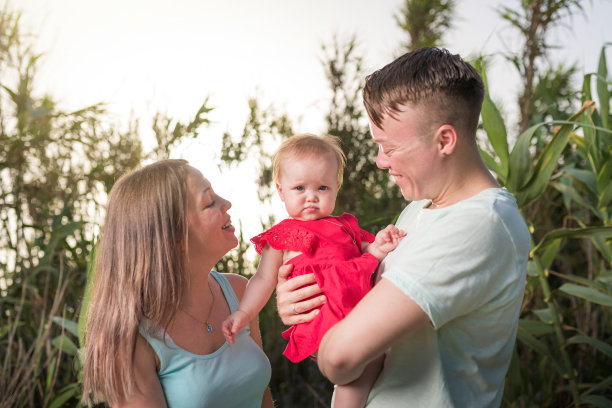 少年快乐家庭户外。父母抱着孩子高兴。他们在一起很快乐。彼此微笑图片下载