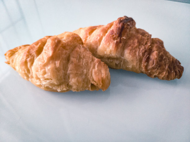 白色的桌子上放着两个羊角面包做早餐图片下载