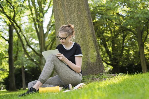 一个学生坐在公园里，在笔记本上写字图片下载