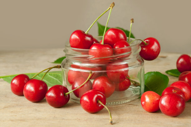 一种早期红樱桃的成熟浆果，带叶子，装在玻璃罐中。收获果实。准备罐头。图片下载