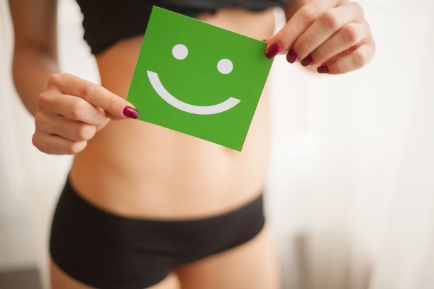 女性健康。健康女性的特写与美丽的Fit苗条的身体在黑色内裤拿着绿卡与快乐的笑脸在手中。胃健康和良好的消化概念。高分辨率图片下载