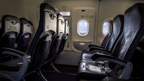 飞机内的座位和窗户。从飞机乘客窗口观看蓝天和白云。图片下载