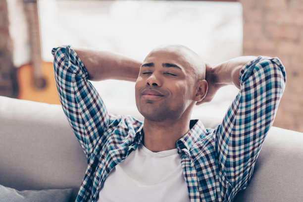 可爱的好男人的近距离照片学生潮人摸手头手掌闭上眼睛坐在沙发沙发沙发穿着格子衬衫大公寓室内安静的空闲时间图片下载