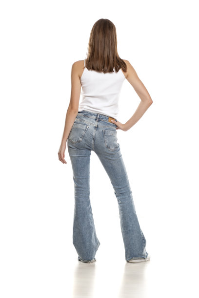 年轻漂亮的女人在白色的背景下摆出喇叭裤的姿势图片下载