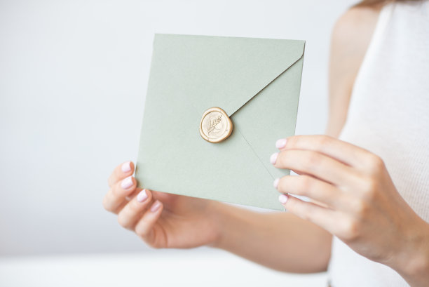 特写照片的女性手拿着一个银色的蓝色或粉红色的邀请信封蜡印章，礼品证书，一张明信片，婚礼请柬。图片下载