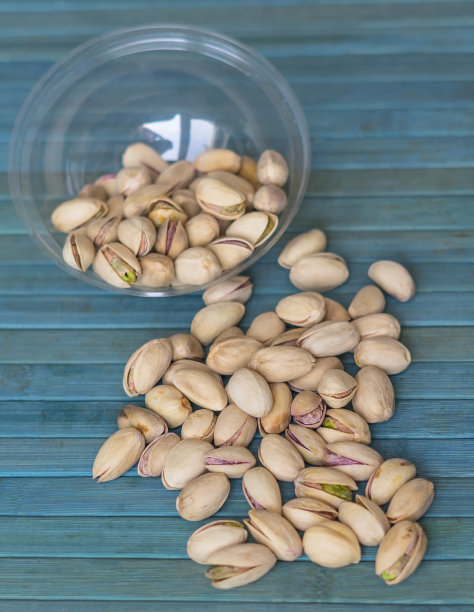 健康的食物背景图片近距离开心果。俯视图果仁开心果在杯盘上图片下载