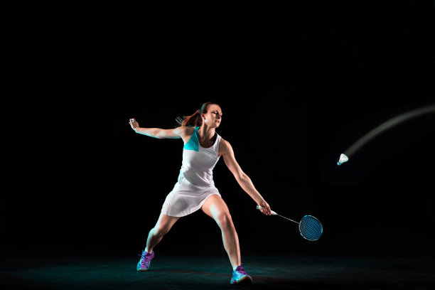 年轻女子打羽毛球孤立在黑色演播室背景图片下载