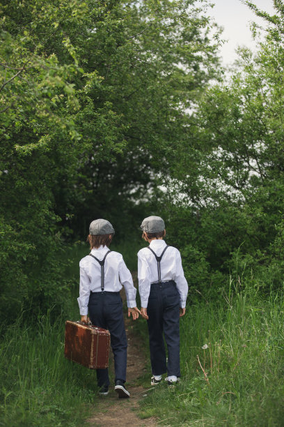 可爱的孩子们穿着复古的衣服、帽子、背带和白衬衫，提着行李箱，在公园里奔跑图片下载