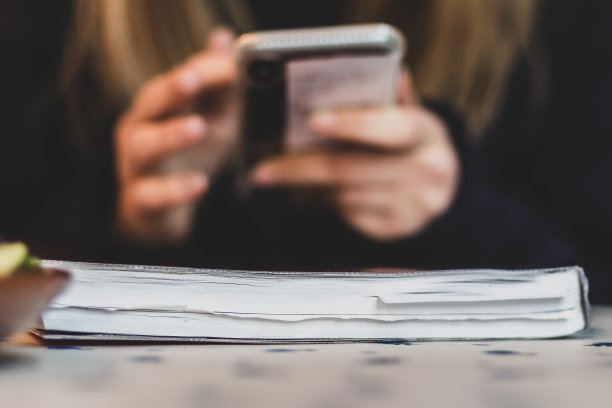 一个十几岁的女孩在餐桌上用手机图片下载