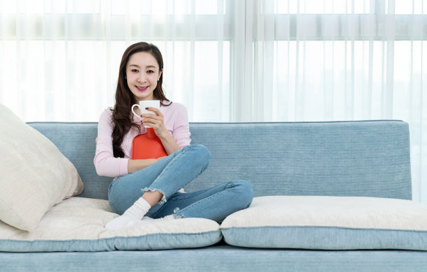 女人坐在沙发上，拿着热水瓶图片下载