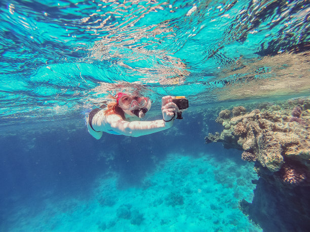 手持运动相机在海中拍摄视频的浮潜女孩图片下载