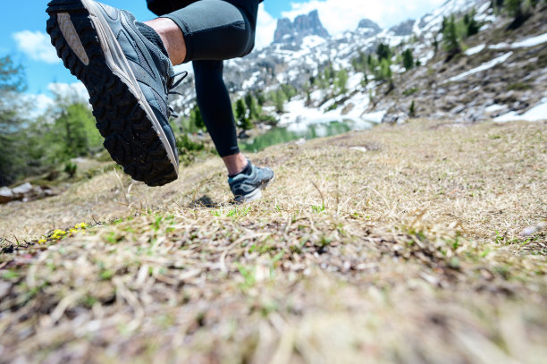 近距离运动员的脚穿运动鞋在户外岩石地形上跑步锻炼。为了健身和健康的生活方式图片下载