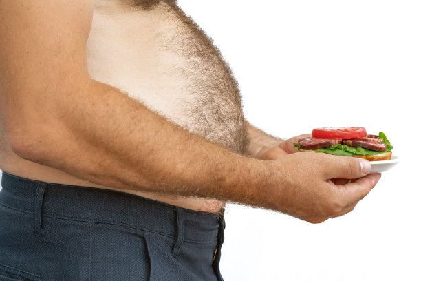 人超重。这张照片是啤酒肚、节食失败和吃错食物的象征。减肥的概念。紧的衬衫。图片下载