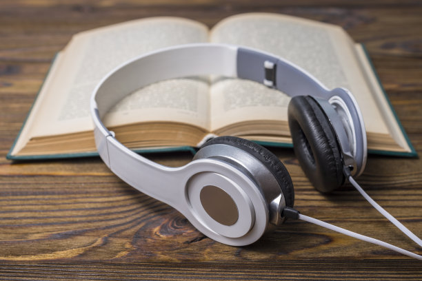 有声书的概念。木桌上放着耳机和旧书。图片下载