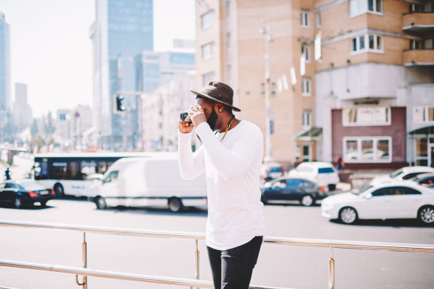 年轻的黑技术潮人通过相机拍摄照片，花空闲时间在市中心的爱好，非洲裔美国男性游客拍照的地方有观光旅游在大都市图片下载
