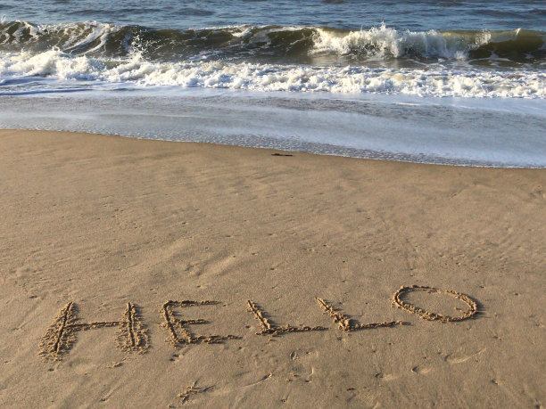 图片上写在阳光沙滩上，用棍子在沙子上写你好字，海浪，概念社交媒体照片上的手写字母在柔软的金色沙滩上，多塞特，英国海边的海岸线图片下载