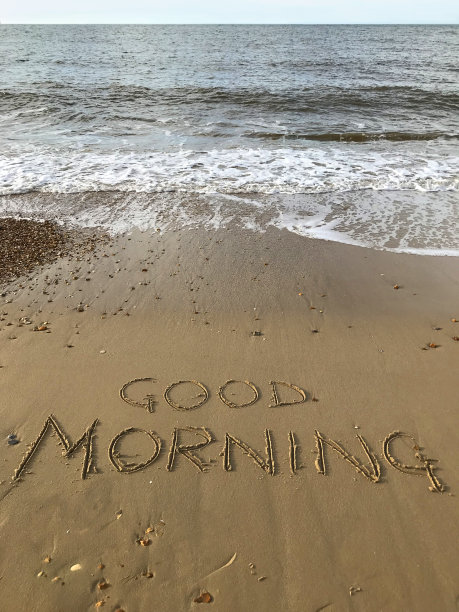 图片写在阳光沙滩上用棍子写在沙子上的早上的话，由海浪，概念社交媒体照片手写字母在柔软的金色沙滩上，多塞特，英国海边的海岸线图片下载