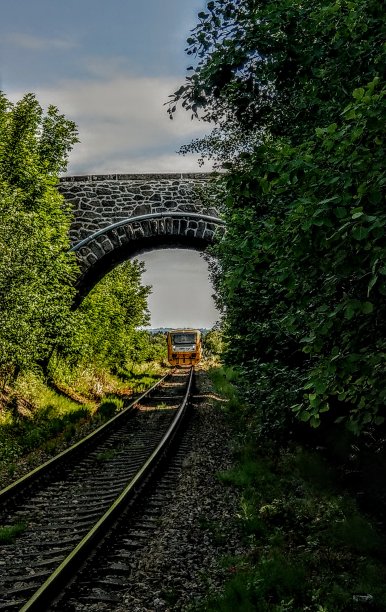 位于波西米亚南部的一座古老的石桥，上面有黄色的火车图片下载