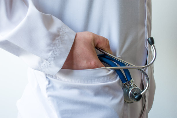 白大褂医生将右手和听诊器放在掌心，放入口袋侧视图。医生对病人进行心血管或呼吸系统诊断时的概念照片图片下载