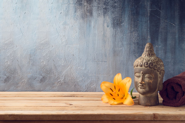 木桌上放置佛像、鲜花和毛巾，背景为黑色图片下载
