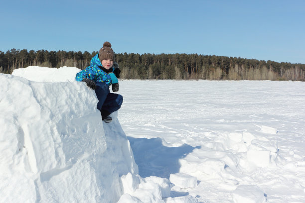 快乐的男孩坐在一个未完工的冰屋冬天图片下载