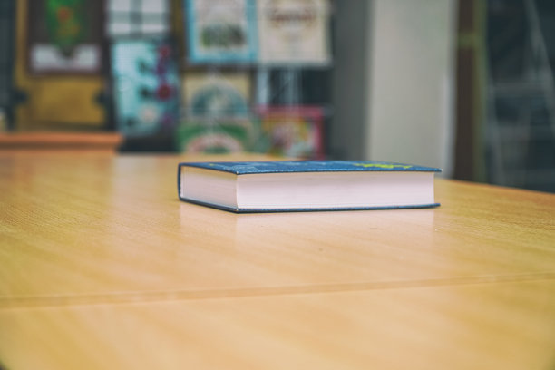 书放在一张木头桌子上，背景是一个模糊的书架图片下载
