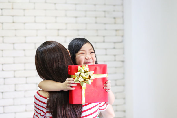 圣诞快乐，节日快乐或者新年快乐。妈妈给孩子们礼物。可爱的女孩给他心爱的妈妈一个礼物。新年的装饰在客厅。图片下载