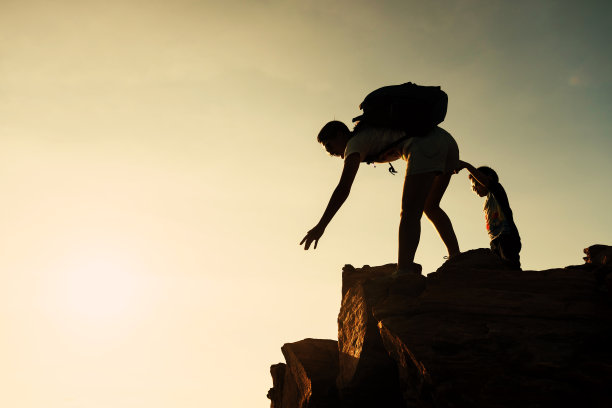 夕阳西下，全家徒步去山顶。帮助的概念图片下载
