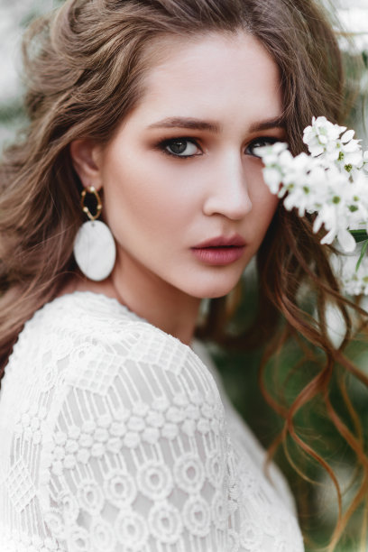 一个美丽的年轻姑娘站在花丛中。图片下载