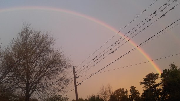 一个绚丽的彩虹在下午与多彩的天空的照片。图片下载