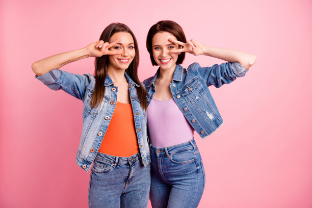 近距离的照片两个美丽的时髦的姐妹，她她最好的女士聚会寒冷的节日情绪拥抱v符号符号近眼睛说你好穿牛仔裤牛仔夹克夹克孤立亮粉色背景图片下载