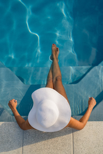 照片模特戴着一顶鲜艳的帽子，悠闲地坐在泳池里图片下载
