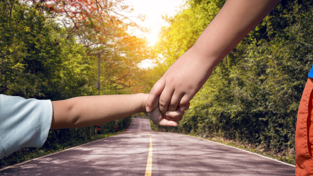 兄妹俩手牵着手，走在阳光灿烂的自然之路上。图片下载