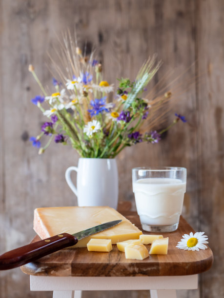 乡村风格的木凳上放着奶酪、牛奶和鲜花图片下载