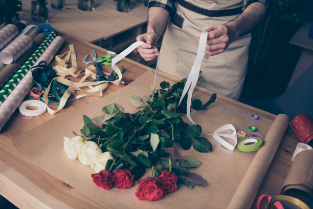 上面高角度裁剪的观点照片的男人家伙手拿白色的丝带使惊喜助理温室花卉植物格子衬衫衣服手工制作图片下载