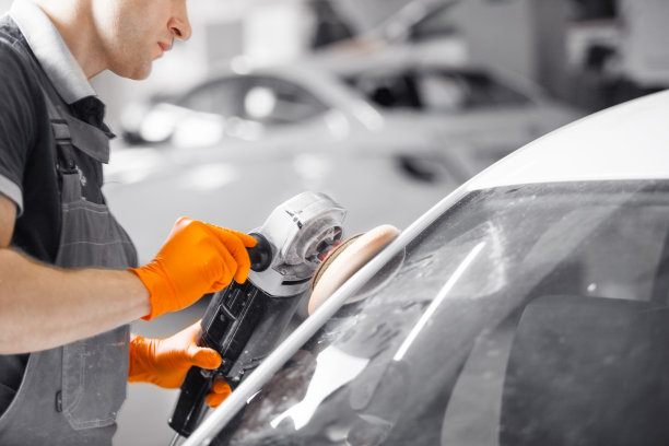 白色汽车抛光，工人用抛光机恢复车身。汽车详细。图片下载