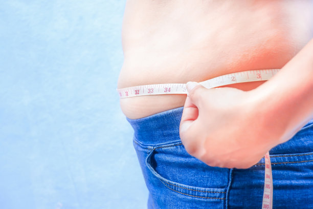 侧视图，胖女人用卷尺量腰围。图片下载