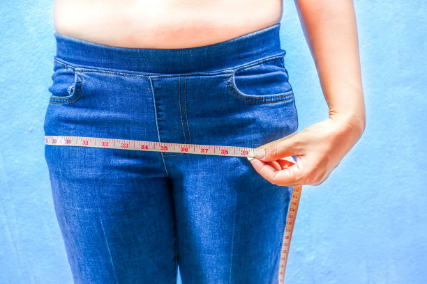 正面图，胖女人用卷尺量她的臀部。图片下载