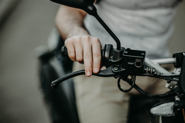 摩托车手的手在把手上踩刹车。图片下载