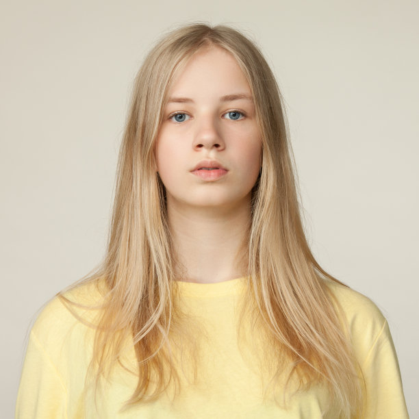 工作室肖像的一个金发少女在黄色t恤米色的背景图片下载