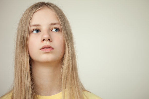 工作室肖像的一个金发少女在黄色t恤米色的背景图片下载