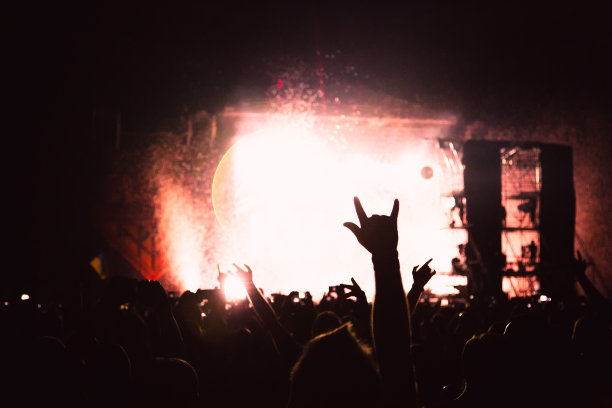 明亮的聚光灯照在跳舞的人们身上。观众为音乐家鼓掌。音乐会人群的剪影。图片下载