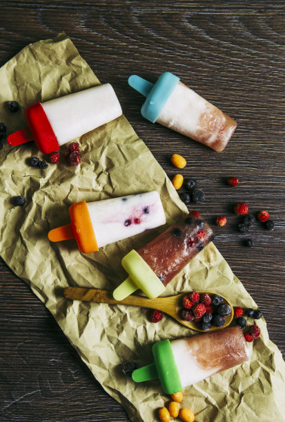 许多家庭制作的冰箱冷冻冰沙酸奶汁冰淇淋与野生浆果在黑暗戏剧性的木制背景的平躺视图。健康的零食概念，非常适合儿童。图片下载