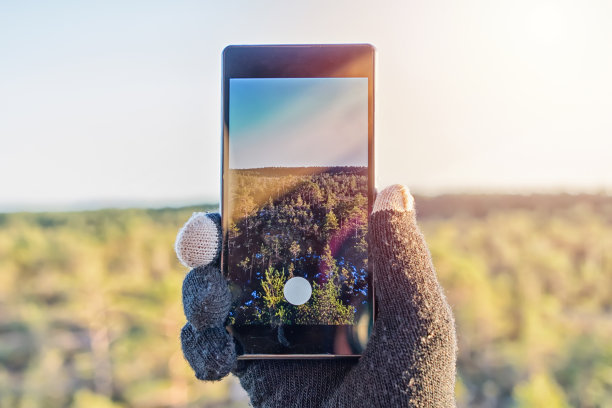 男性的手拿着智能手机和拍照的特写图片下载