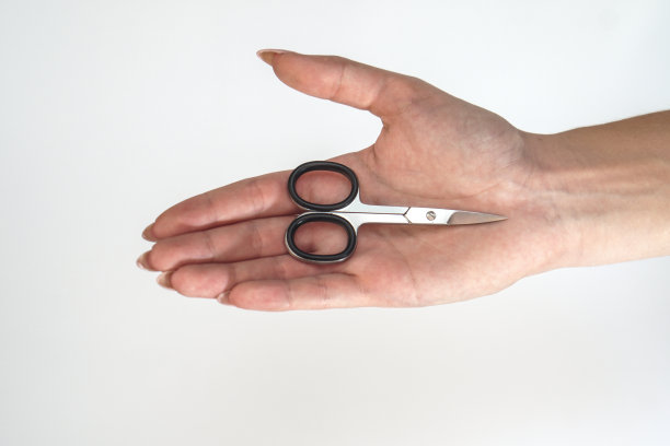 一个小女孩手上拿着修指甲的剪刀。女性美容和身体护理。库存图片图片下载