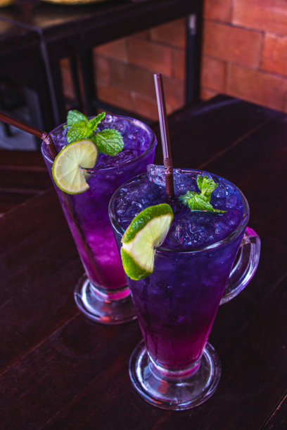 蝴蝶豌豆汁与柠檬在透明的玻璃上放在深棕色的木桌是泰国草药饮料的健康和提神。选择重点。图片下载