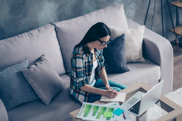 靠近顶部上面高角度的视图照片美丽的她她的女士计划者做笔记笔记本视频教训学习统计穿specs牛仔裤牛仔格子衬衫坐在舒适的沙发房子客厅室内图片下载