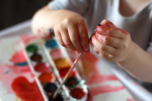 照片孩子用脏手触摸画笔。以水彩画为背景图片下载