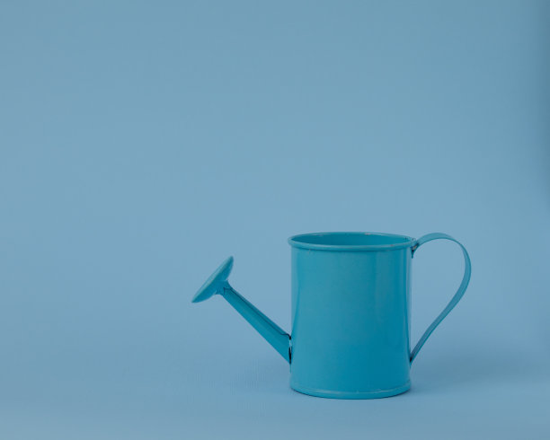 蓝色背景下的玩具蓝色喷壶。图片下载