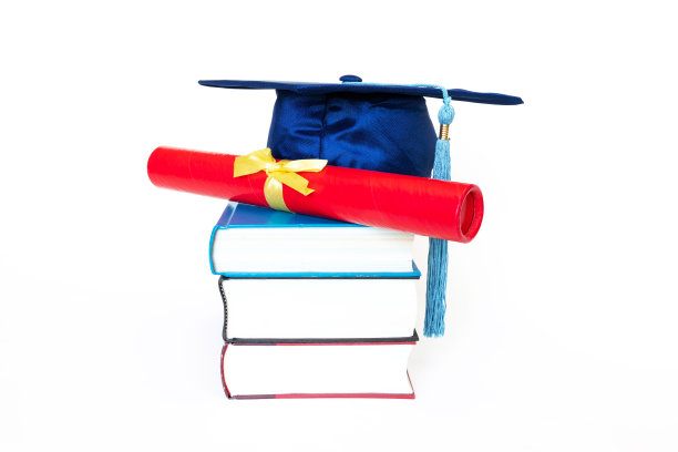 毕业帽与文凭上的书孤立在白色的背景图片下载